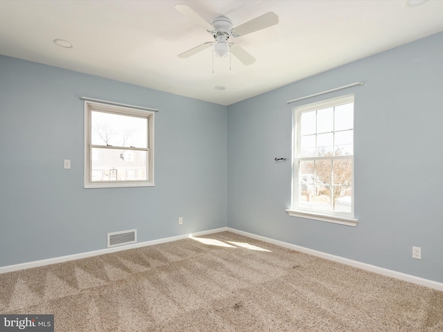 carpeted empty room with visible vents, baseboards, and a ceiling fan