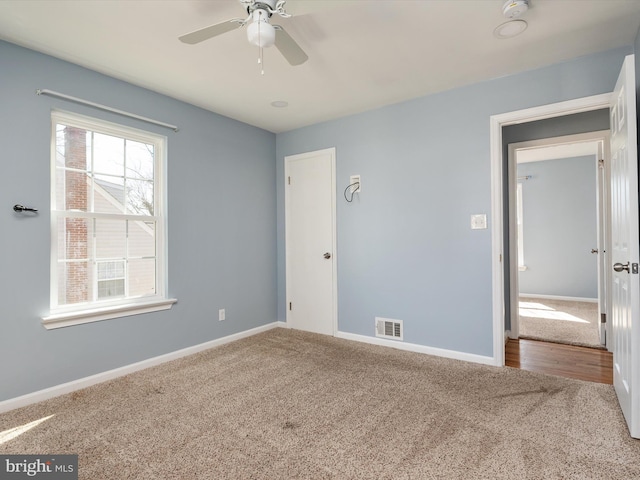 spare room with carpet, baseboards, visible vents, and ceiling fan