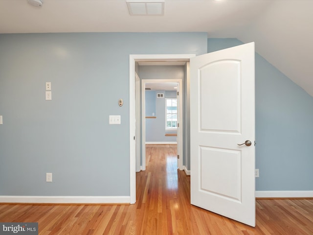 hallway featuring visible vents, baseboards, and light wood-style flooring