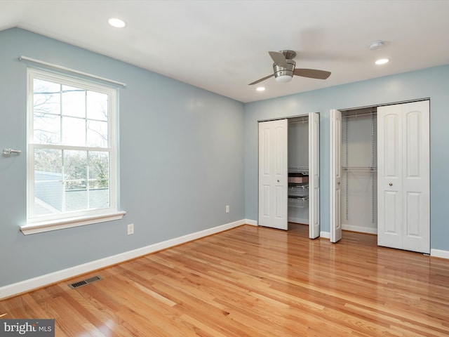 unfurnished bedroom with light wood-style floors, visible vents, two closets, and baseboards