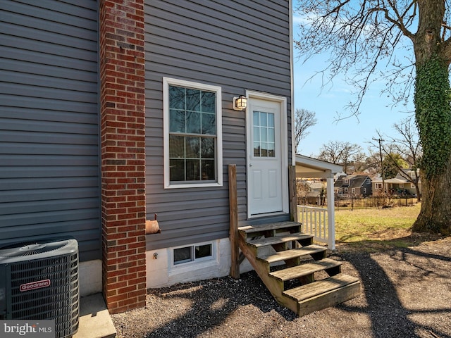 property entrance with cooling unit and brick siding