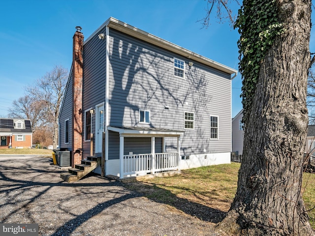 back of property featuring central air condition unit, a yard, and a chimney