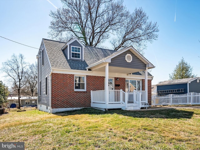 view of front of house featuring brick siding, a shingled roof, a front lawn, fence, and a porch