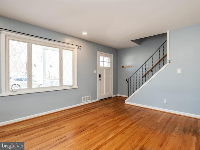 entrance foyer with visible vents, stairs, baseboards, and wood finished floors