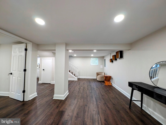 below grade area featuring dark wood finished floors, recessed lighting, stairs, and baseboards