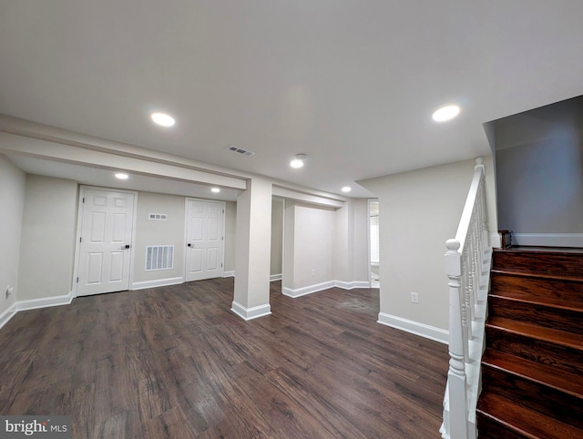 finished basement with visible vents, baseboards, dark wood finished floors, and stairway