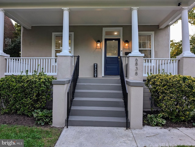 view of exterior entry with covered porch and stucco siding