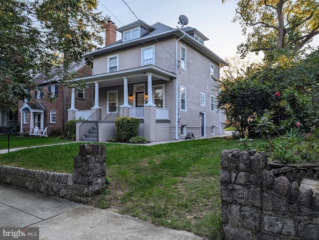 traditional style home with covered porch, a front lawn, and stucco siding