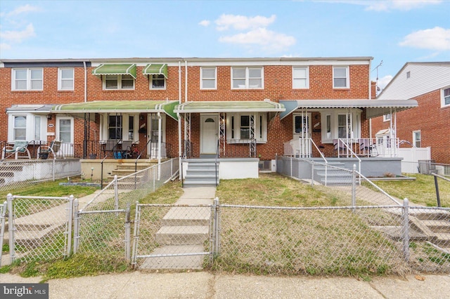 view of property featuring a front lawn, a gate, brick siding, and a fenced front yard