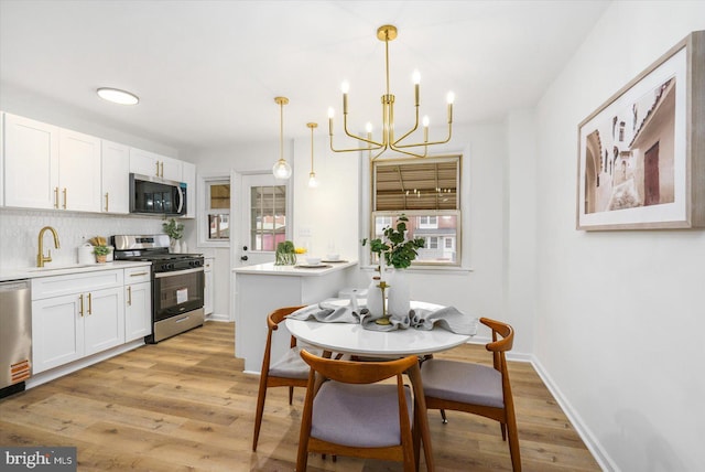 kitchen featuring a chandelier, light wood-style flooring, white cabinets, and stainless steel appliances