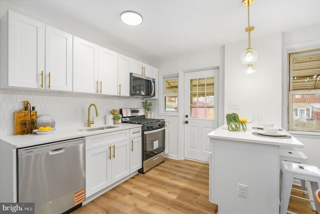 kitchen with white cabinetry, a kitchen bar, appliances with stainless steel finishes, and a sink