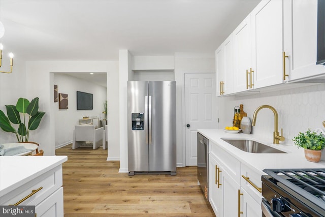 kitchen with white cabinetry, stainless steel appliances, light countertops, and a sink