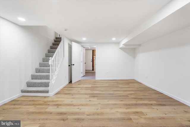 finished basement featuring stairway, recessed lighting, baseboards, and light wood finished floors