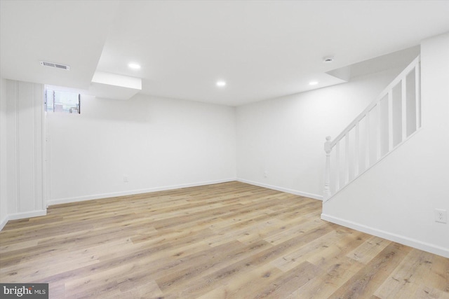 finished below grade area with baseboards, visible vents, recessed lighting, stairs, and light wood-type flooring