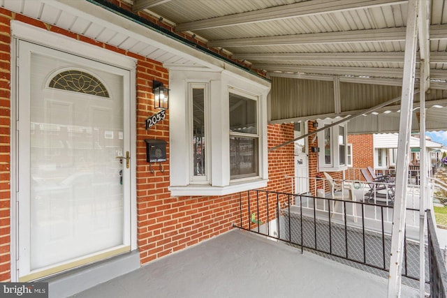 entrance to property with covered porch and brick siding