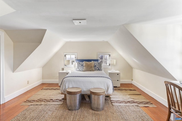 bedroom with baseboards, wood finished floors, and lofted ceiling