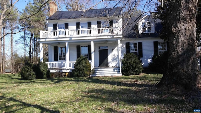 view of front of property featuring a balcony, a chimney, a front lawn, and covered porch