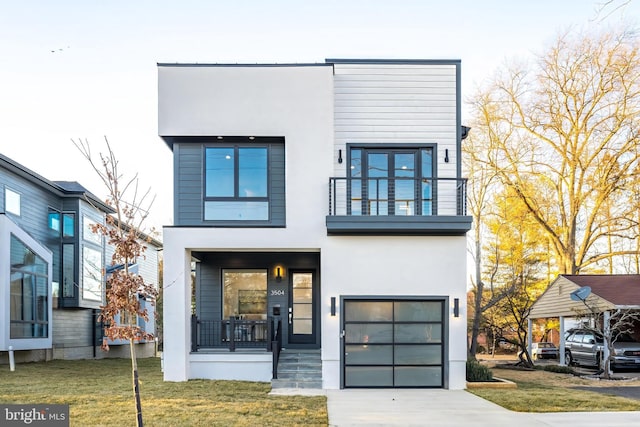 contemporary house with stucco siding, a front lawn, covered porch, a garage, and a balcony