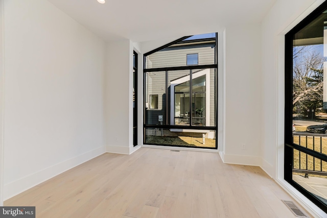 spare room with visible vents, baseboards, and wood finished floors