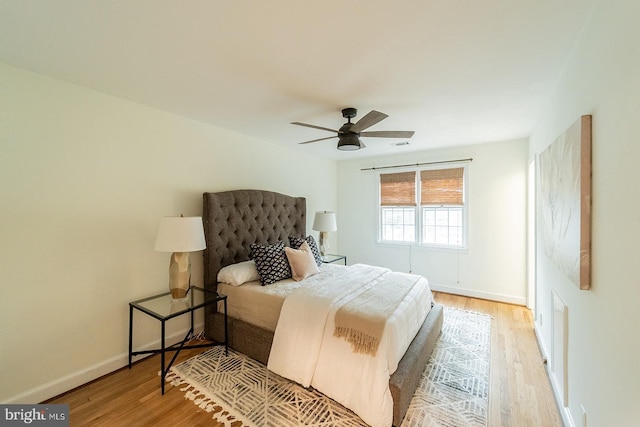 bedroom with a ceiling fan, visible vents, light wood-style floors, and baseboards