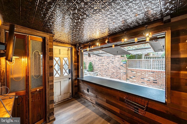 doorway with an ornate ceiling, wooden walls, and wood finished floors