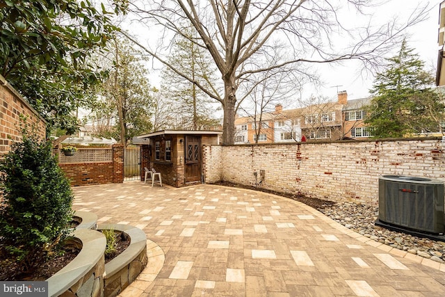 view of patio / terrace with cooling unit, an outbuilding, and a fenced backyard