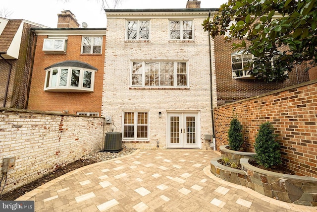 rear view of property featuring central air condition unit, a patio, french doors, brick siding, and a chimney