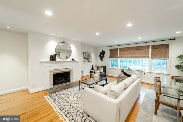 living area featuring a fireplace with flush hearth, recessed lighting, and light wood-style floors