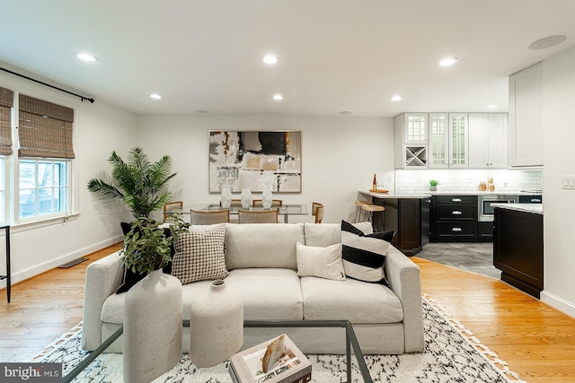 living room featuring recessed lighting, baseboards, and light wood finished floors