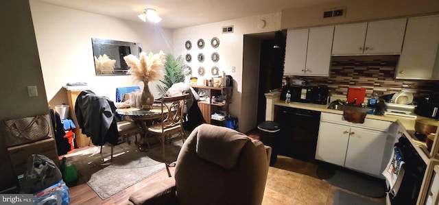 kitchen with tasteful backsplash, light countertops, black dishwasher, and visible vents