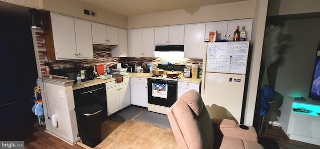 kitchen featuring under cabinet range hood, light countertops, range with gas stovetop, decorative backsplash, and freestanding refrigerator