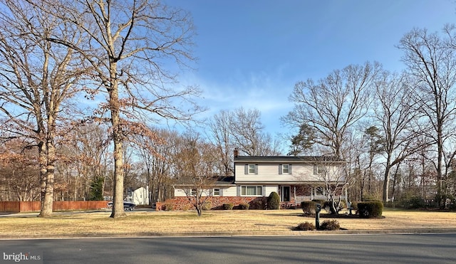 traditional-style home featuring a front lawn, a chimney, and fence