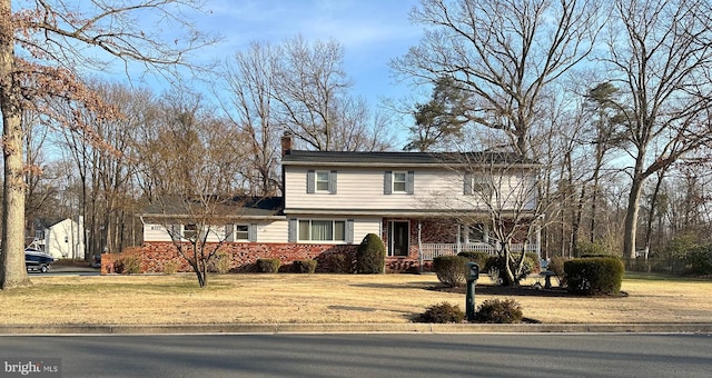 traditional-style home with a front lawn, a porch, and a chimney