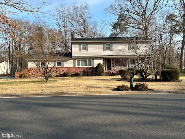 traditional home featuring a porch, a chimney, and a front yard