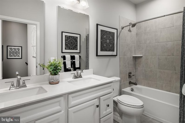 full bath with a sink, toilet, double vanity, and shower / bathtub combination