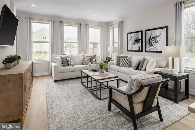 living room featuring a wealth of natural light, light wood-type flooring, and baseboards