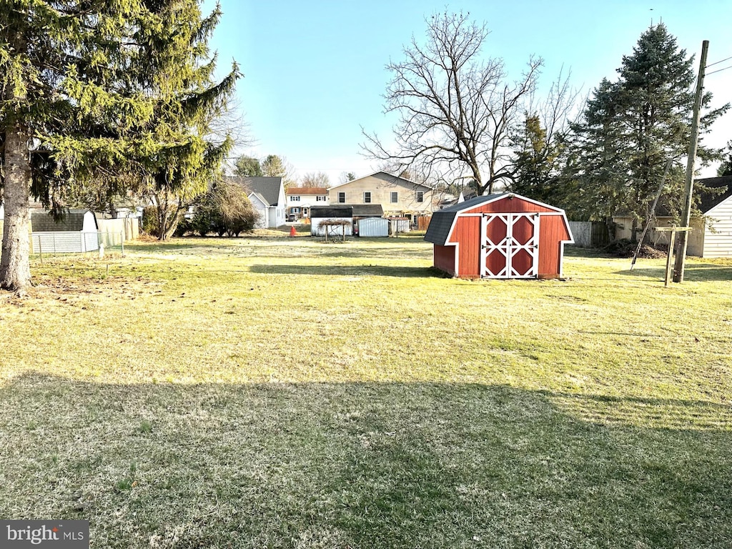 view of yard with a storage shed, an outdoor structure, and fence