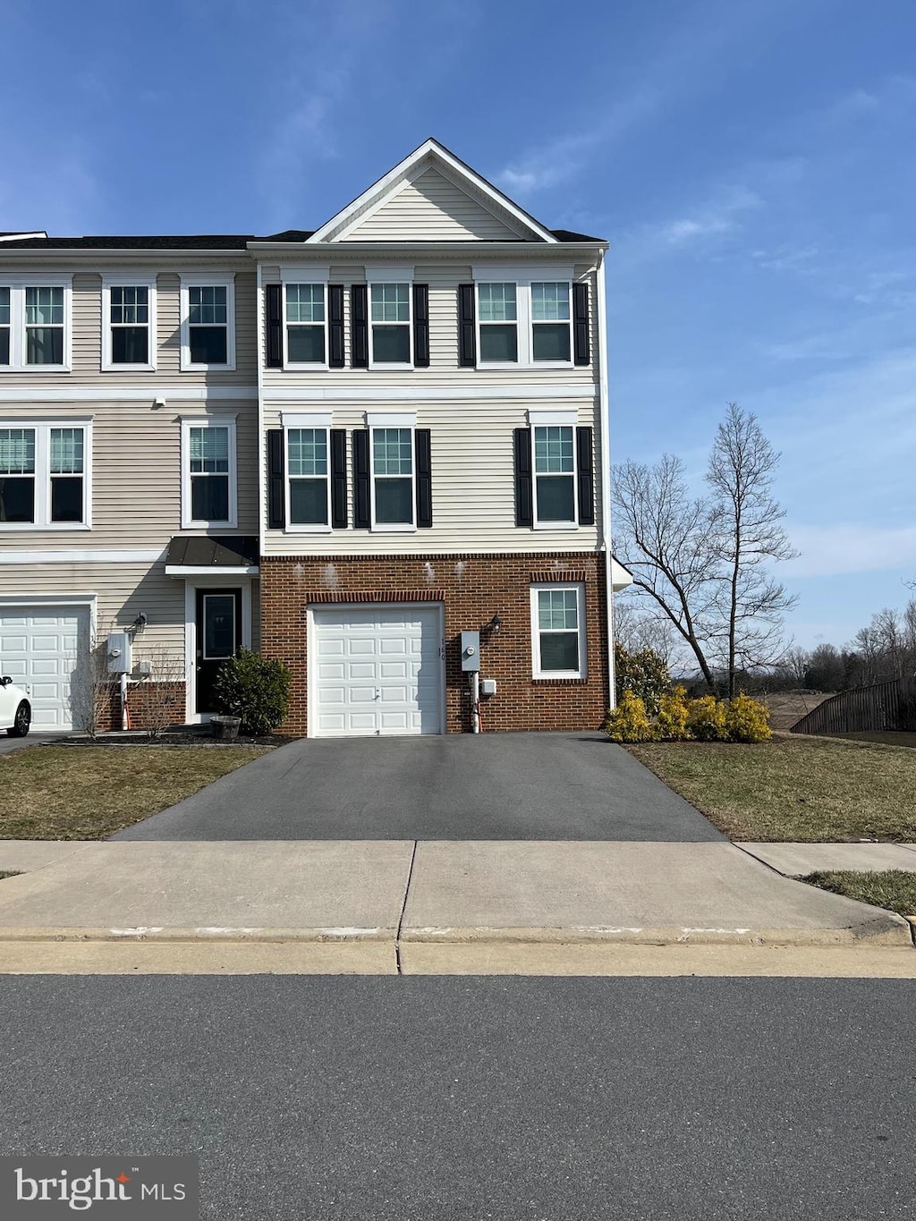 view of property featuring aphalt driveway, a garage, and brick siding