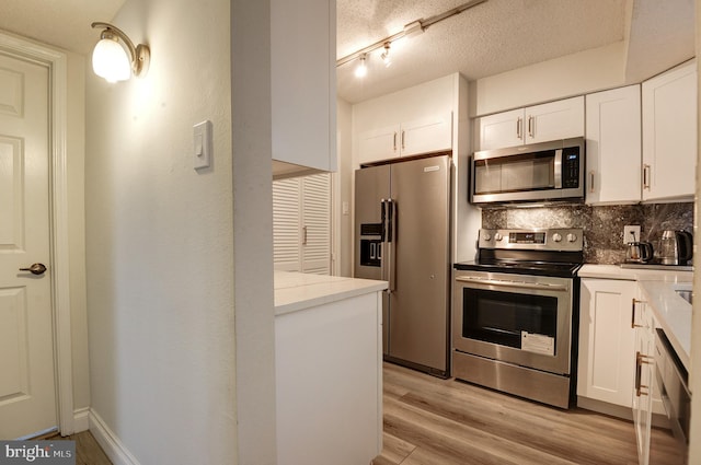 kitchen with stainless steel appliances, light wood-style floors, a textured ceiling, white cabinetry, and backsplash