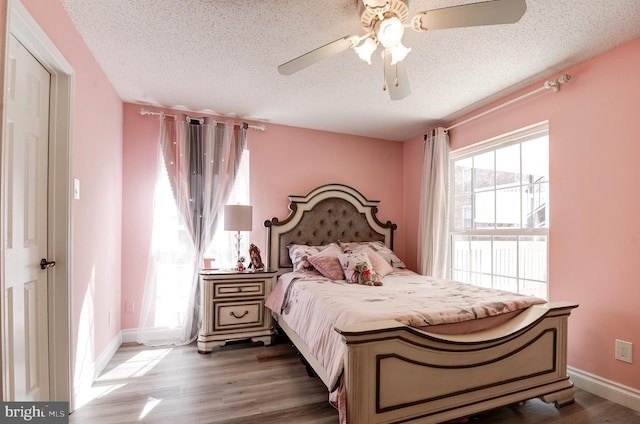 bedroom with a textured ceiling, a ceiling fan, baseboards, and wood finished floors