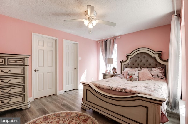 bedroom featuring baseboards, ceiling fan, a textured ceiling, and light wood-style floors