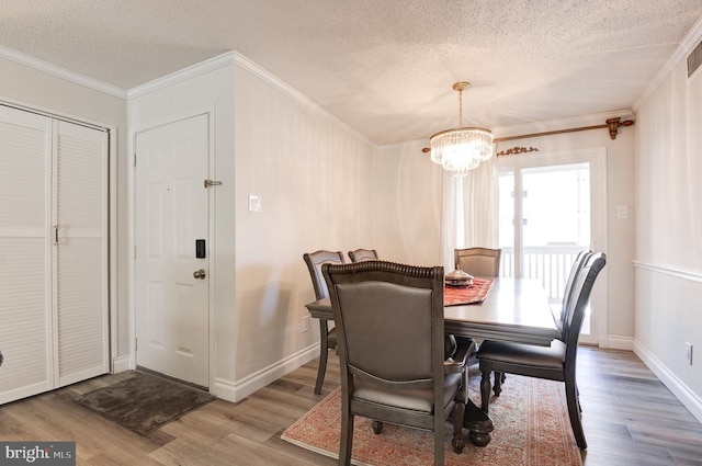 dining space featuring a textured ceiling, crown molding, and wood finished floors