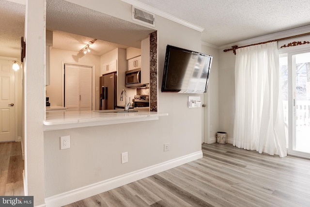 kitchen with wood finished floors, visible vents, a sink, appliances with stainless steel finishes, and a textured ceiling