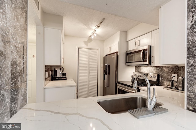 kitchen with light stone counters, backsplash, appliances with stainless steel finishes, and white cabinets