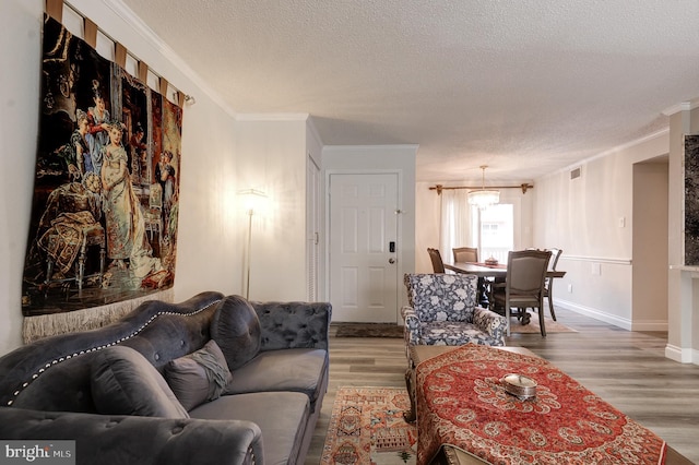 living room featuring baseboards, a textured ceiling, wood finished floors, and crown molding