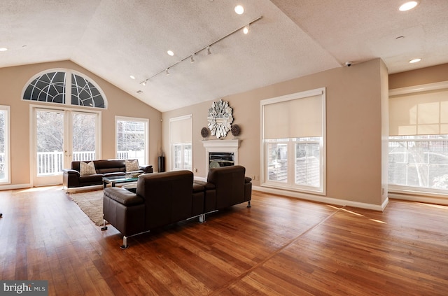 living room featuring hardwood / wood-style floors, lofted ceiling, a textured ceiling, and a glass covered fireplace