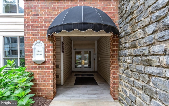 view of exterior entry featuring french doors and brick siding