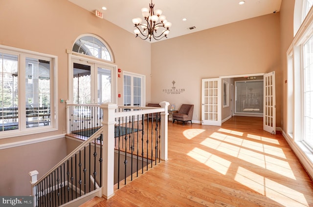 foyer with visible vents, french doors, a high ceiling, an inviting chandelier, and wood finished floors