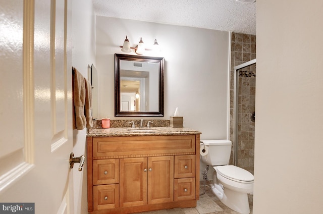 bathroom featuring a tile shower, toilet, vanity, and a textured ceiling