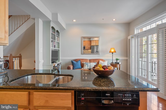 kitchen with wood finished floors, a sink, stainless steel fridge with ice dispenser, dark stone counters, and recessed lighting